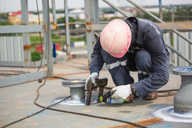 Mannelijke werknemer test mondstuk tank stomplas koolstof dakplaat van opslagtank olie achtergrond wit contrast van magnetisch veld