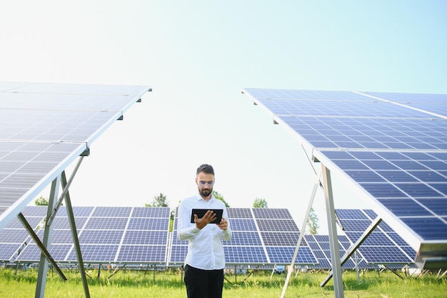 Mannelijke werknemer zonne-energiecentrale met een tablet op een achtergrond van fotovoltaïsche panelen