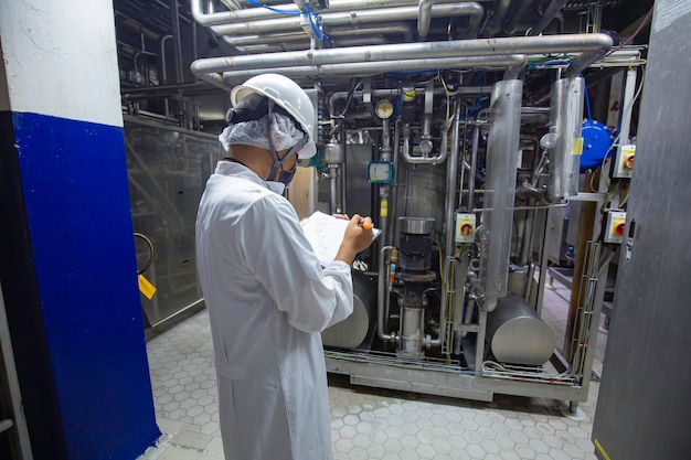 Mannelijke werknemers inspecteren ultrasone roestvrijstalen verticale stalen tanks en leidingen met apparatuurtank chemische kelder