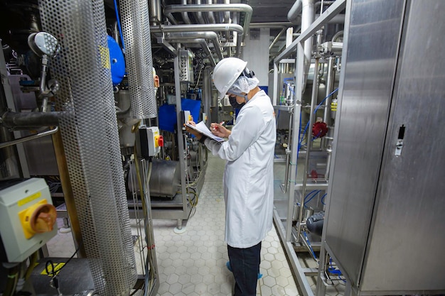 Foto mannelijke werknemers inspecteren ultrasone roestvrijstalen verticale stalen tanks en leidingen met apparatuurtank chemische kelder