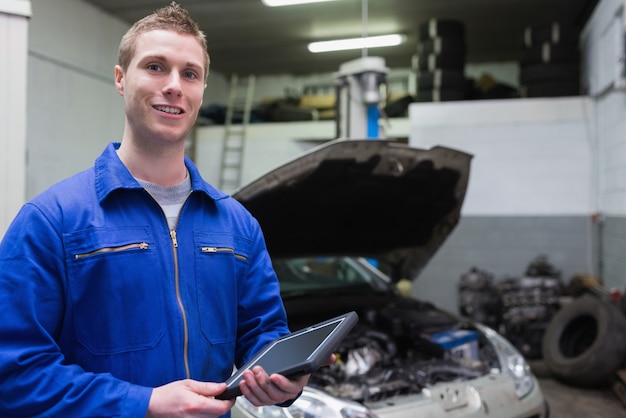 Mannelijke werktuigkundige met digitale tablet bij garage