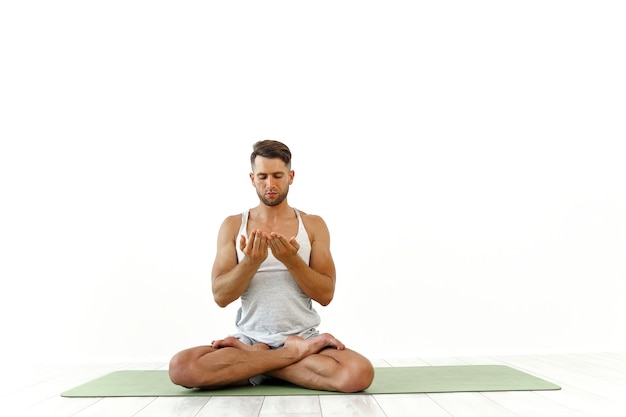 Mannelijke yoga maditaten in klassieke pose in studio op wit