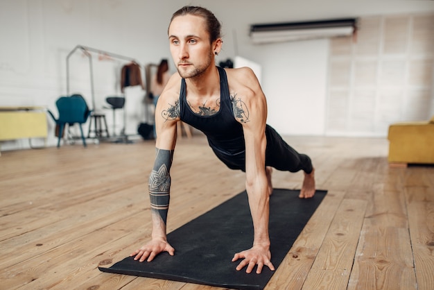 Mannelijke yoga met tatoeage aan kant doen push-up oefening in de sportschool met grunge interieur. fitnesstraining binnenshuis