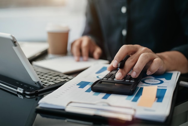 Mannelijke zakenman die aan bureaubureau werkt met het gebruiken van een calculator om de aantallen te berekenen, het boekhoudingsconcept van de financiën.
