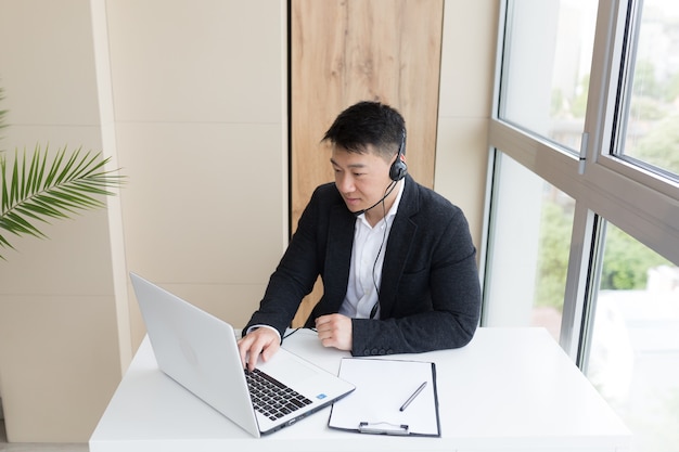 Mannelijke zakenman geeft online training met een headset en laptop