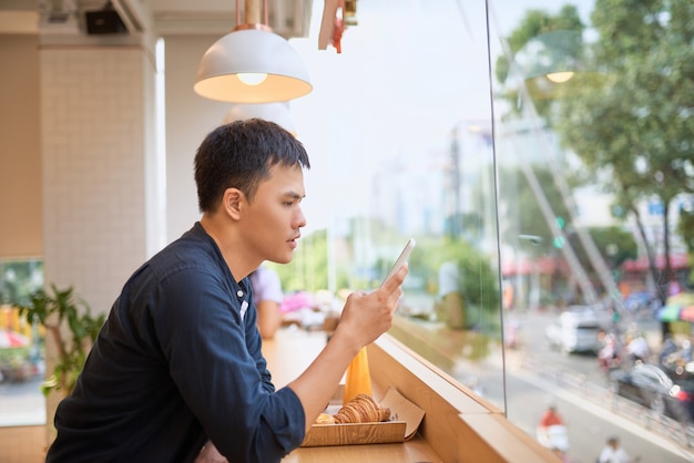 Mannelijke zoekopdrachten hadden informatie nodig op de internetwebsite via een smartphone terwijl ze op een terrascafé zaten met sap en zoet dessert