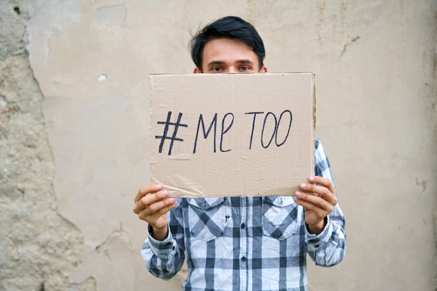 Mannen alleen met depressieve uitdrukking en tonend een papier met een metoo-tekst metoo als nieuwe bewegingsidentificatie...