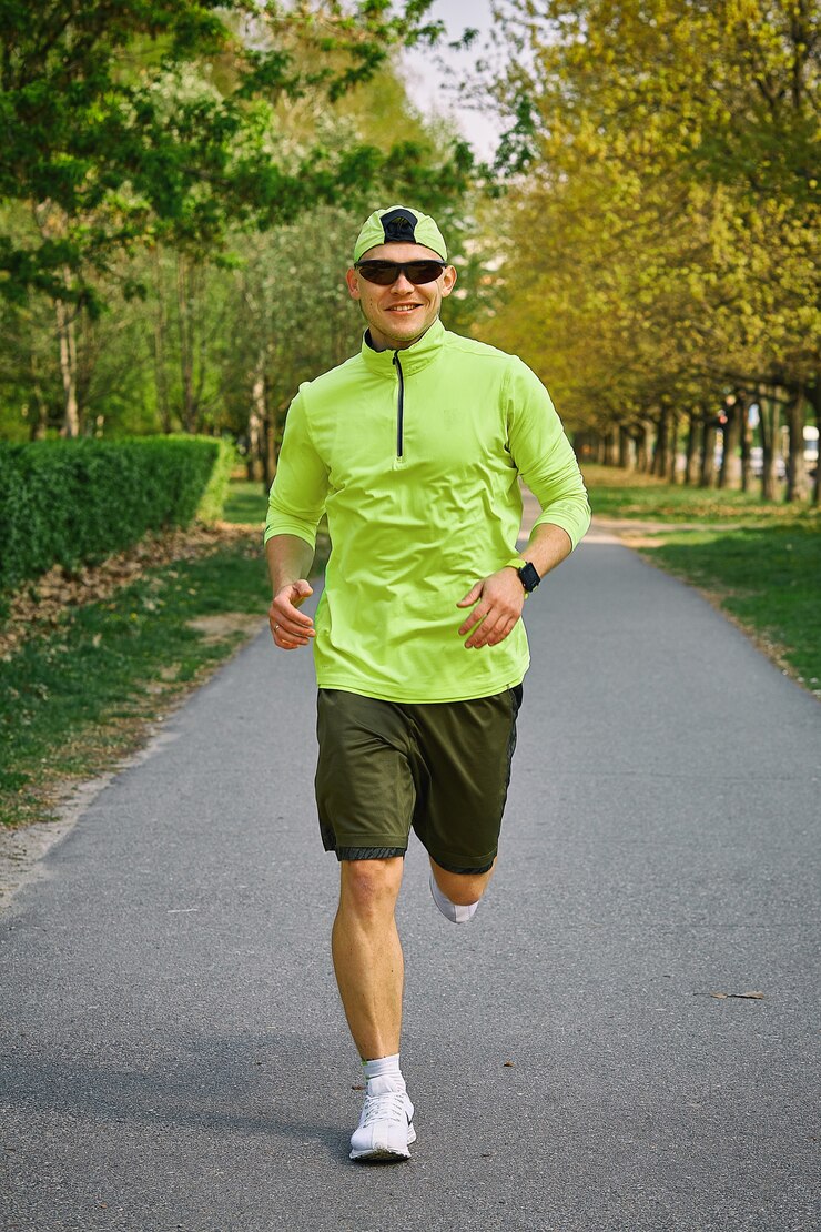 Mannen atleet in groene jas draait op het stadspark.