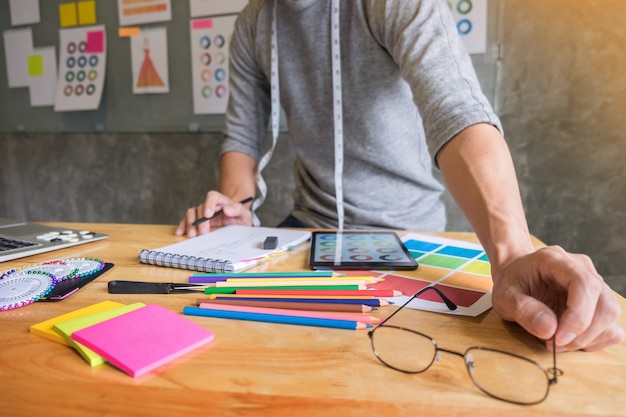 mannen die als modeontwerper kiezen op kleurkaart voor kleding in digitale tablet op werkplaatsstudio.