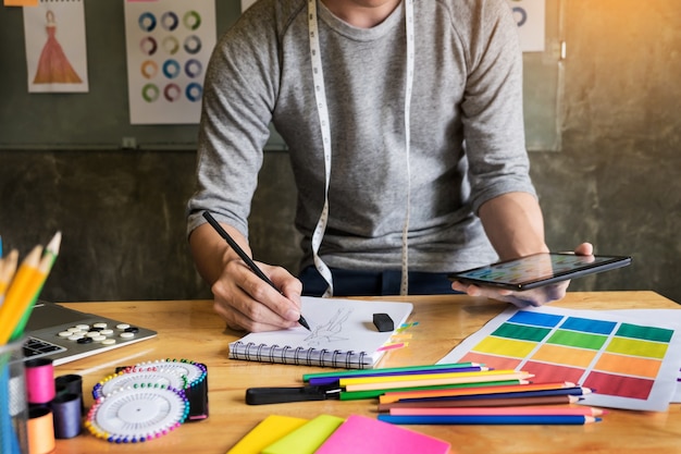 Mannen die als modeontwerper tekeningsketsen werken voor kleding in atelierpapier op werkplaatsstudio.