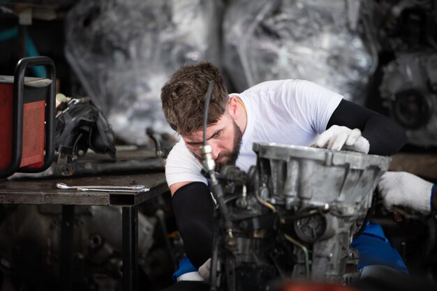 Mannen die de motor van een auto repareren in een auto-reparatiewerkplaats Selectieve focus