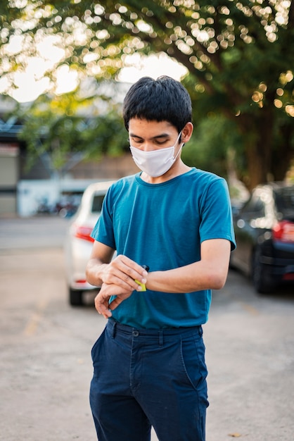 Mannen die een gezichtsmasker dragen ter bescherming tegen Coronavirus of Covid-19, staan te kijken naar het horloge om de pols.