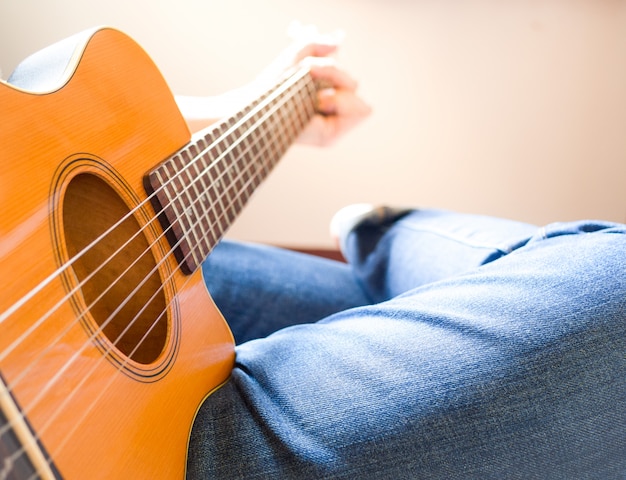 Mannen dragen een spijkerbroek en zitten akoestische gitaar.