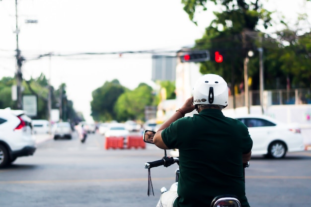 Mannen dragen groene jassen en witte helmen, rijden motorfietsen, parkauto's, wachten op verkeerslichten.