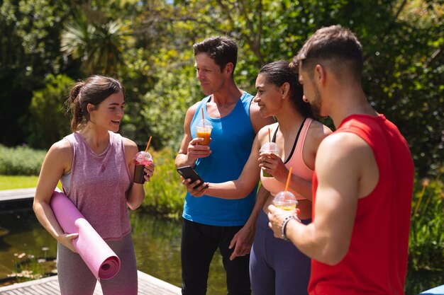 Foto mannen en vrouwen in sportkleding met gezonde drankjes na de training in het park. gezonde levensstijl, drank en fitness.