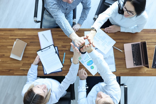 Mannen en vrouwen op kantoor aan hun bureau geven elkaar vijf handen. Business concept ontwikkeling