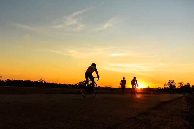 Mannen fietsen op de weg met prachtige kleurrijke avondlucht. Sport en actief leven concept.