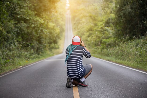 mannen fotograaf met een camera in het wild en op de weg voor een foto