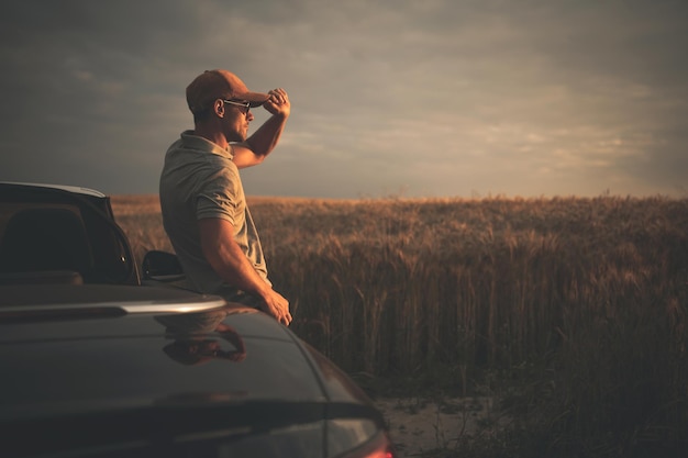 Foto mannen genieten van de zonsondergang op het platteland terwijl ze voor plezier rijden