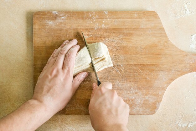 Mannen handen snijden rauw deeg