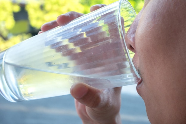 Mannen heffen het glas om water te drinken om de dorst te lessen op warme dagen.