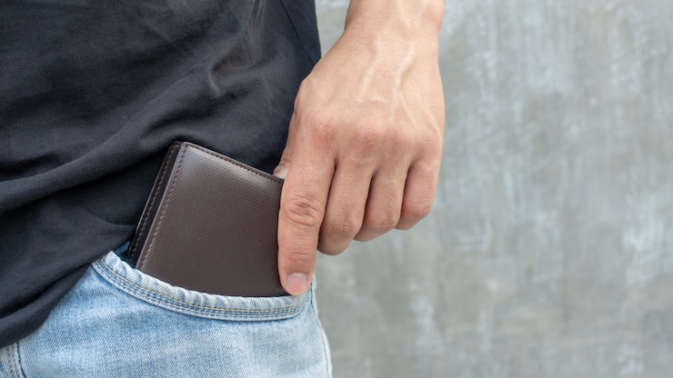 Mannen houden een bruine portefeuille uit een jeanszak.
