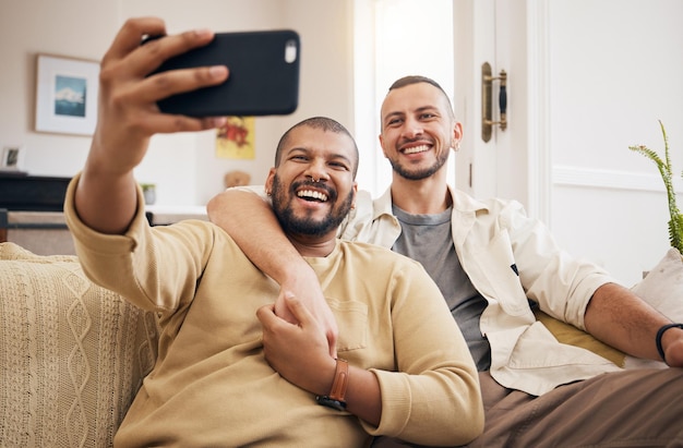 Mannen lgbtq paar en grappige selfie in de woonkamer van het huis binden en lachen samen homoseksuele mensen en profiel foto gelukkige herinnering of glimlach op sociale media in liefde zorg en interraciale knuffel op de bank