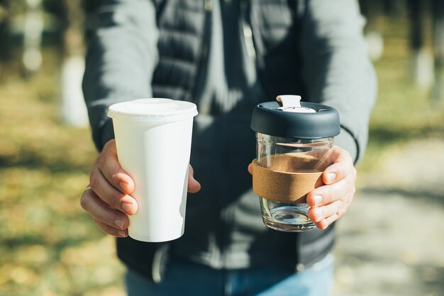 Mannen met afhaalmaaltijden koffiekopje en wegwerp papieren beker met plastic deksel. Bewuste keuze. Geen afvalconcept