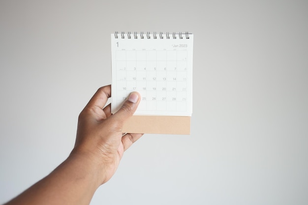 Mannen met een kalender van 2023 tegen een witte muur