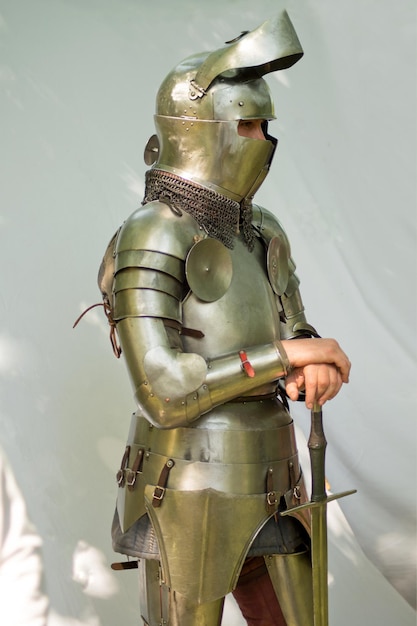 Mannen met oude helm en zwaard. Een vintage europees full body armor pak geïsoleerd tegen een witte achtergrond.