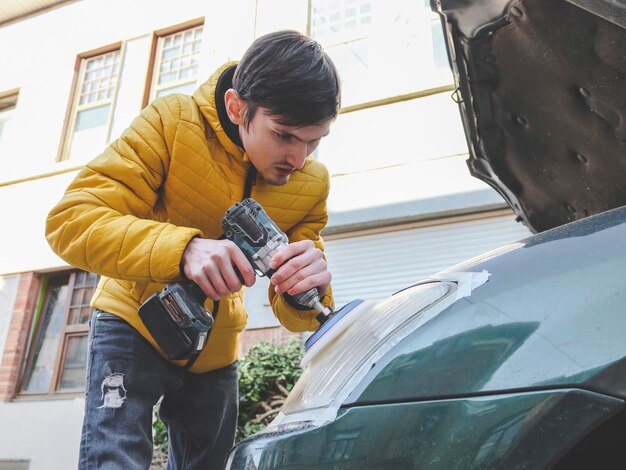 Foto mannen polijsten de koplamp van een auto met een boor en een sponsschijf