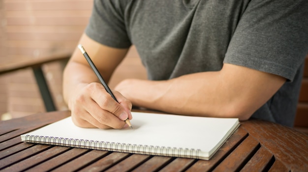 Mannen schrijven van een boek op een houten tafel.