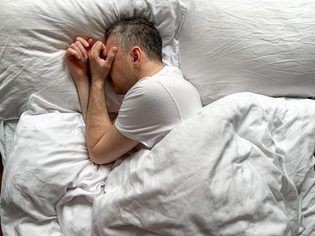 Foto mannen van middelbare leeftijd slapen thuis gezellige slaapkamer bed vibes witte ochtend concept van comfort ontspanning