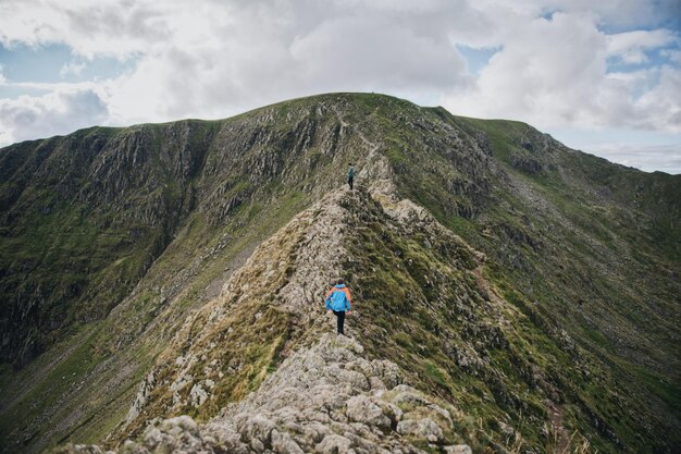 Mannen wandelen op de berg tegen een bewolkte hemel.