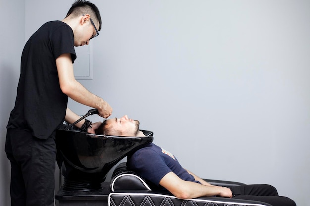 Mannen wassen hun haar in een kapperszaak een man maakt een knipbeurt in een schoonheidssalon comfort concept