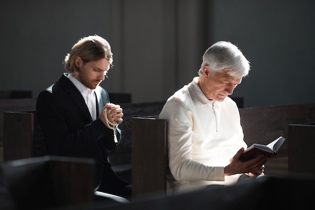 Mannen zitten op de bank en bidden in de kerk tijdens de mis