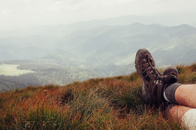 Mannenbenen in bruine schoenen die op de berg liggen