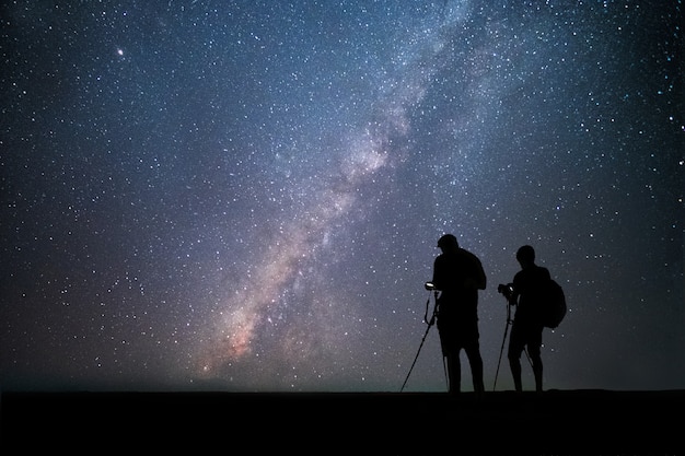 Mannenfotograaf die zich dichtbij de camera bevinden en foto melkachtige manier en sterren nemen