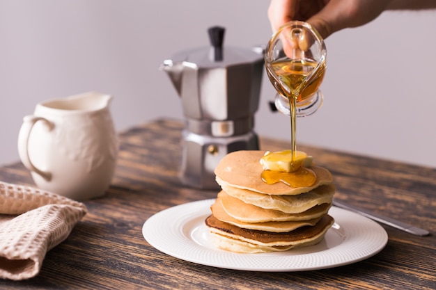 Mannenhand ahornsiroop gieten op lekkere pannenkoeken.