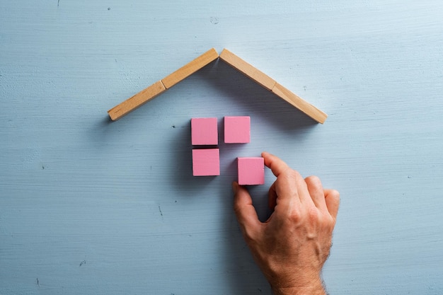 Mannenhand bouwen van een huis van roze houten blokken