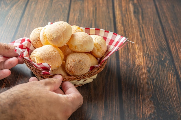 mannenhand die pão de queijo of kaasbrood oppakt