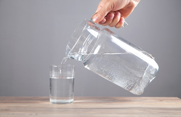 Mannenhand die water in glas giet. gezonde drank