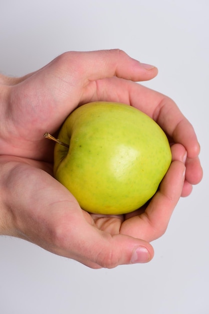 Mannenhand houdt lichtgroene appel in palmen Voedsel en gezonde levensstijl concept Apple geplaatst op lichtgrijze achtergrond Apple in heldere en sappige kleur bovenaanzicht