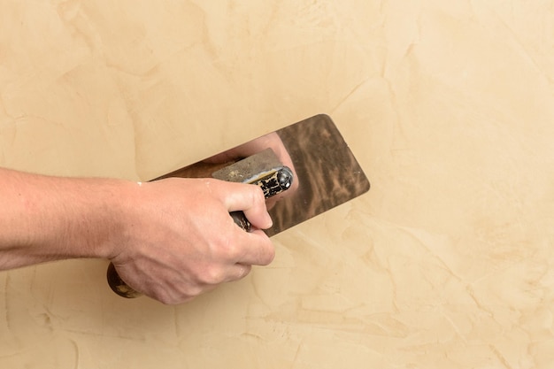 Mannenhand legde een Venetiaanse doek op de muur