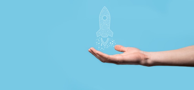 Mannenhand met digitale transparante raket pictogram. Opstarten bedrijfsconcept. Raket lanceert en zweeft vliegen. Concept van bedrijfsidee.