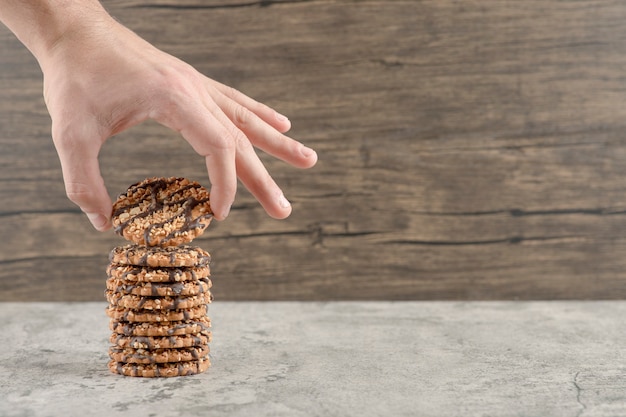 Mannenhand met een havermoutkoekje met chocoladesiroop op een houten.