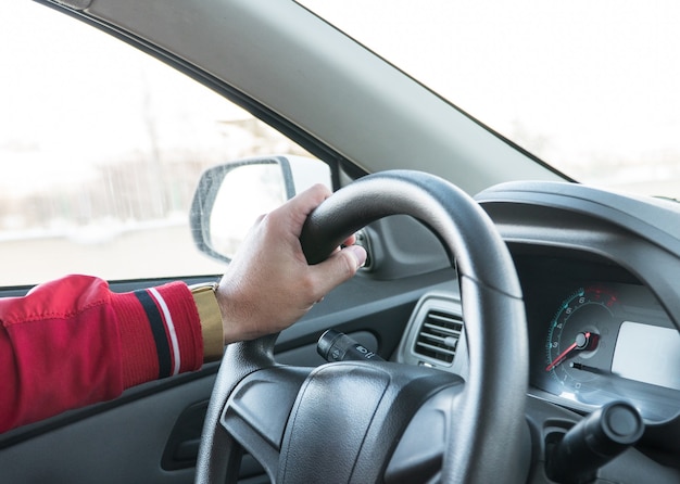 Mannenhand met een horloge aan het stuur van een moderne auto