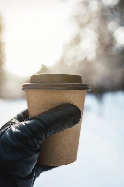 Mannenhand met een papieren kopje warme koffie tijdens koude winterdag