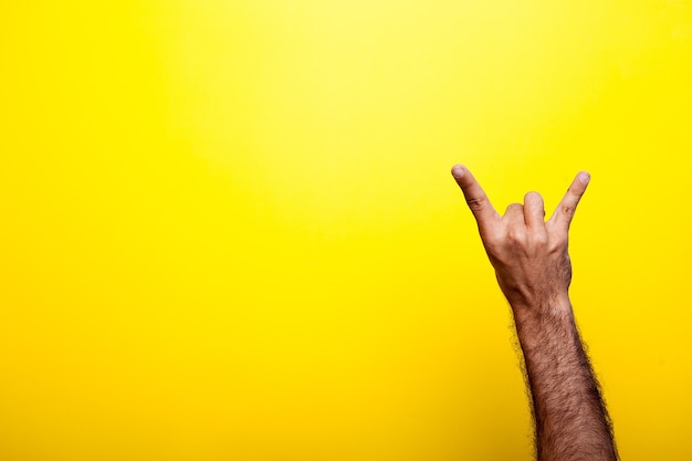 Mannenhand met een rots op teken op gele achtergrond