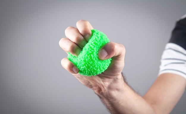 Mannenhand met groene stressbal.